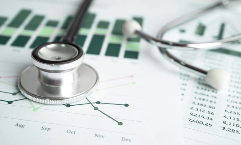 A stethoscope resting on printed charts and data tables