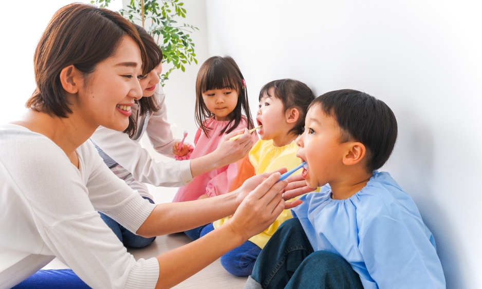 A caregiver helping young children brush their teeth