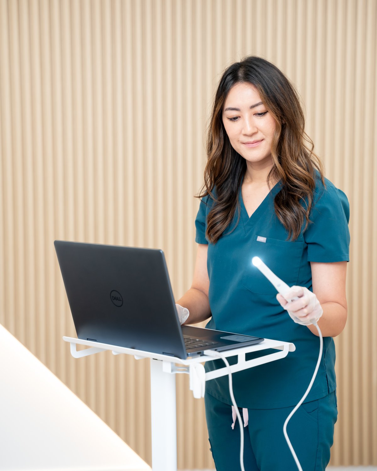 An OroMed teammate at the rolling cart, holding the intraoral camera used for preventive dental evaluations